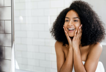 happy BIPOC woman admiring skin
