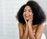 happy BIPOC woman admiring skin