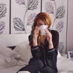 red haired woman drinking tea in bed