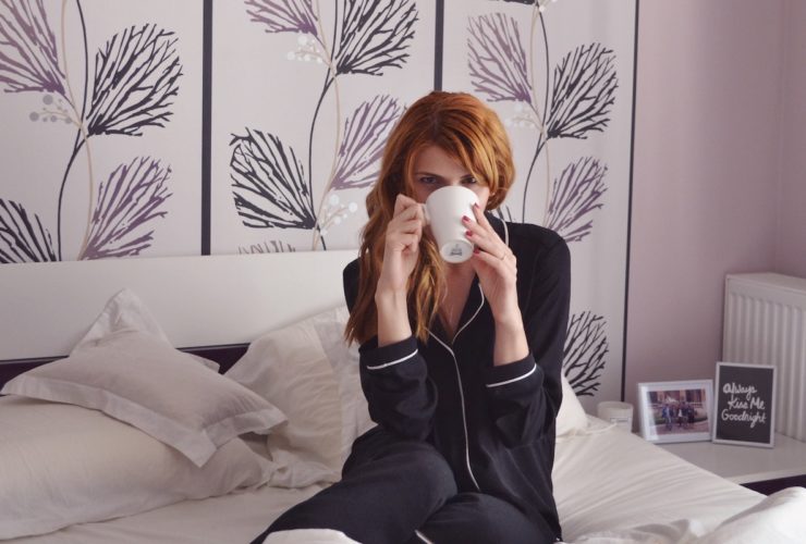 red haired woman drinking tea in bed