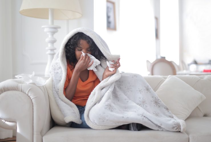 woman on couch sick sneezing