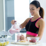 woman smiling making smoothie before workout