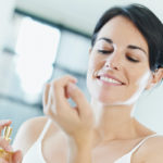 smiling woman applying perfume