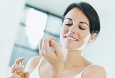 smiling woman applying perfume
