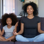 BIPOC mother and daughter meditating together