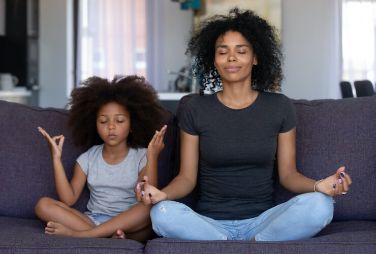 BIPOC mother and daughter meditating together