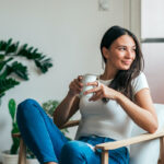 Beautiful young woman drinking coffee. Can adding this 1 spice to your coffee or tea help manage symptoms of PCOS?