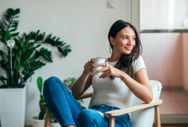 Beautiful young woman drinking coffee. Can adding this 1 spice to your coffee or tea help manage symptoms of PCOS?