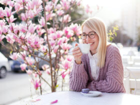 Young woman drinking coffee at city streets. Attractive happy girl smiling
