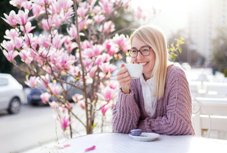 Young woman drinking coffee at city streets. Attractive happy girl smiling