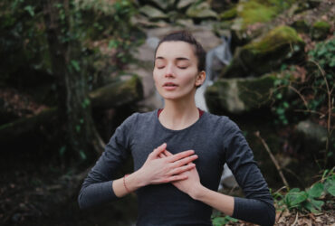 Young woman practicing breathing yoga pranayama outdoors in moss forest