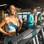 Happy athletic people jogging on treadmills in a health club