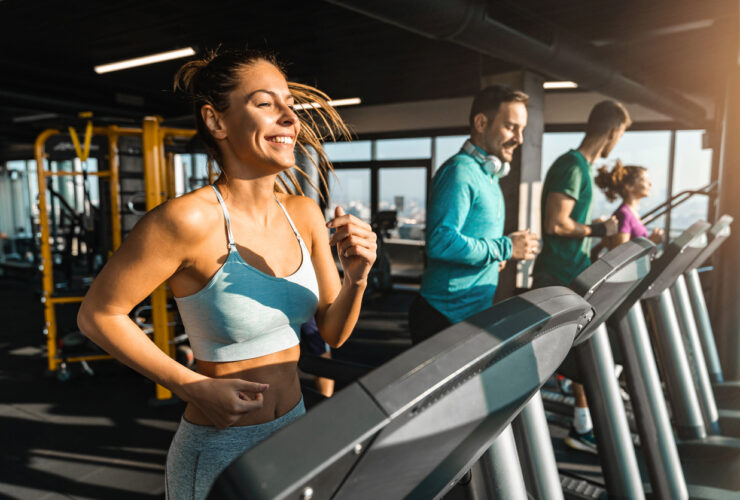 Happy athletic people jogging on treadmills in a health club