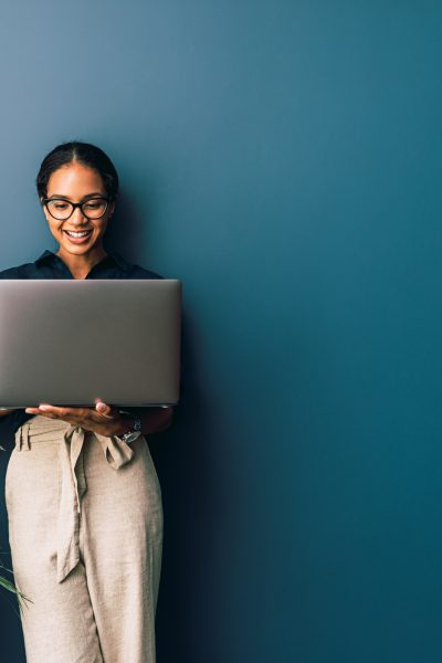 Beautiful businesswoman standing at home and holding laptop computer oh hands