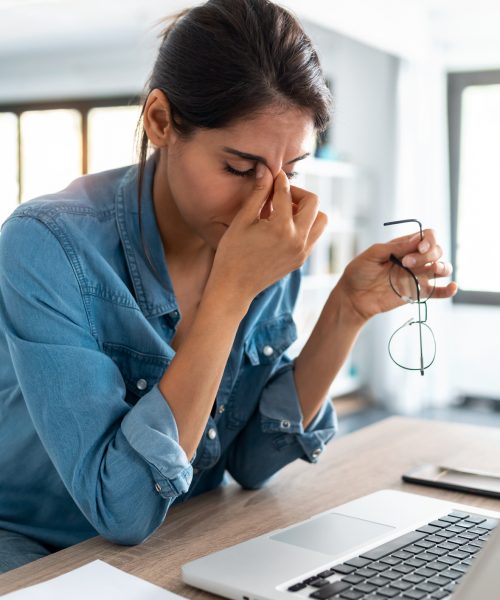 Stressed business woman working from home on laptop looking worried, tired and overwhelmed.